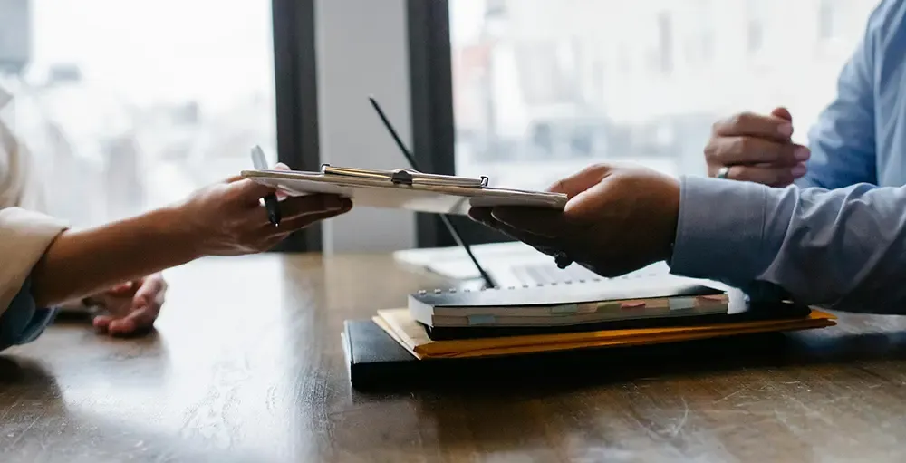 employee passing paperwork to HR manager
